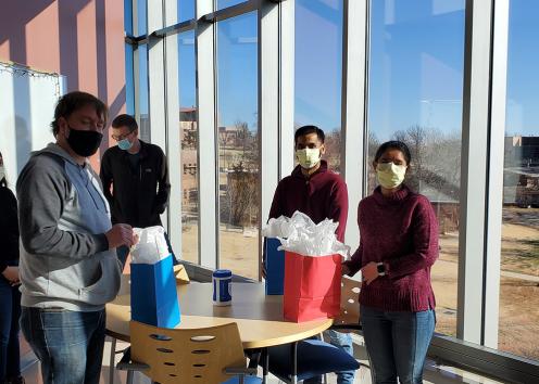 Group of people with masks in interaction area of MRB with presents in front of them.